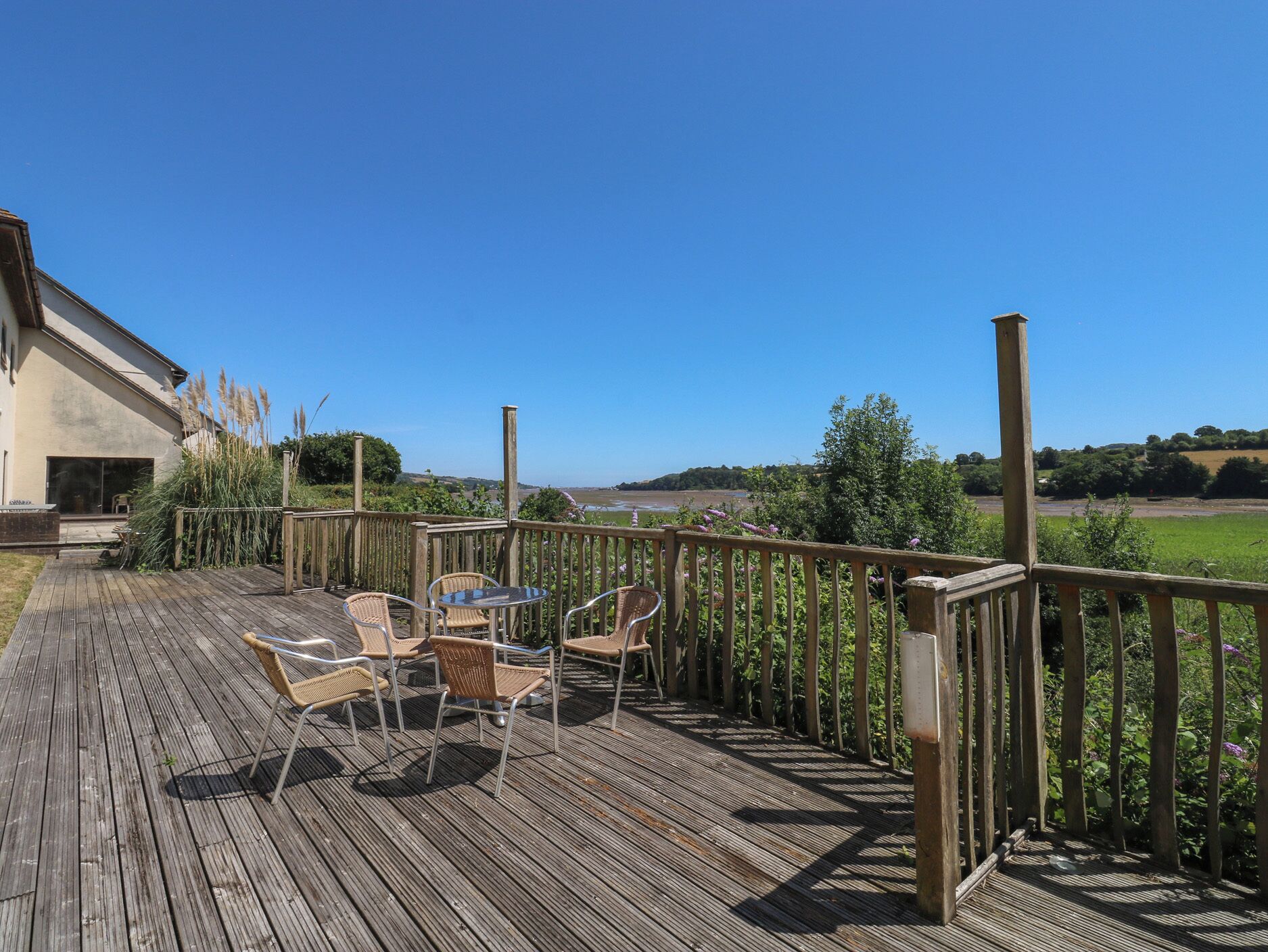 A wooden deck with outdoor furniture and a view of the countryside.