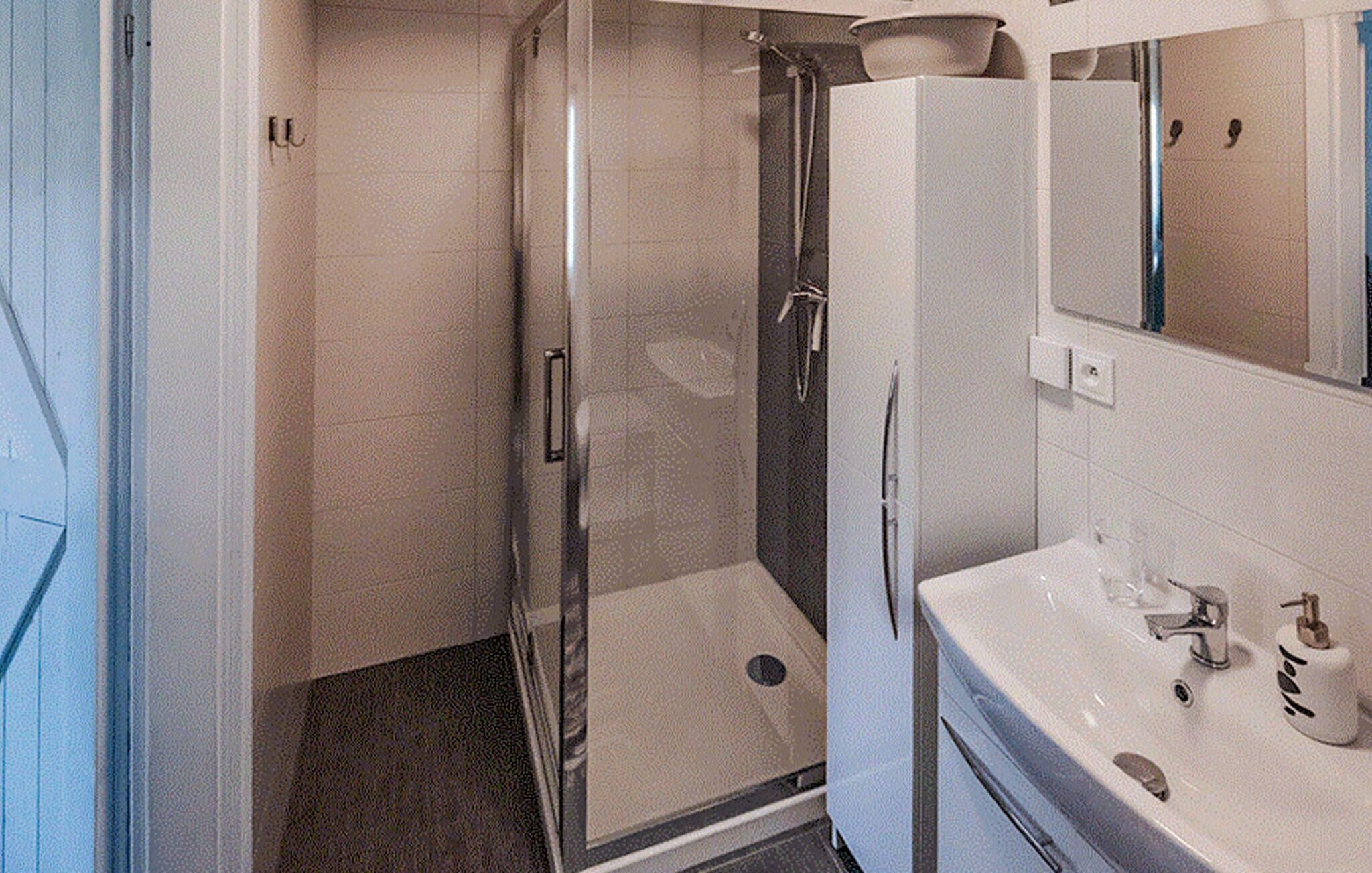 Ein Badezimmer mit Duschkabine, Waschbecken mit Spiegel und Toilette.
