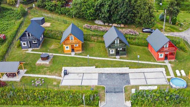 A cluster of houses with distinct roofs, a swimming pool, and a paved area with a sign.