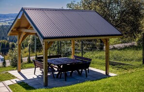 Un pavillon en bois doté d’un toit incliné, d’une table et de bancs.