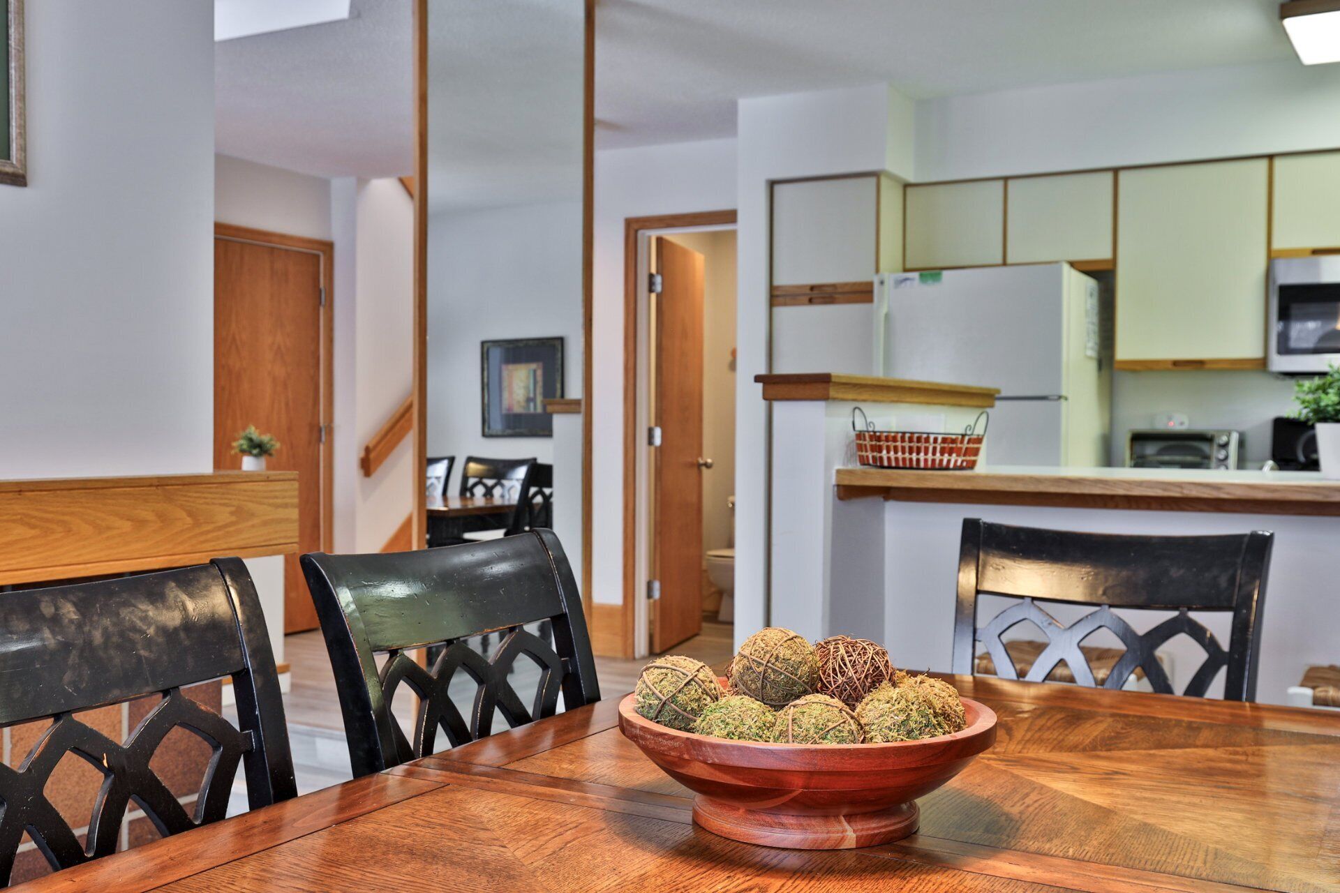 A dining table with a bowl of spherical food items, surrounded by chairs with a geometric back design.