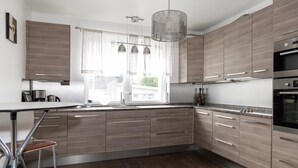 A modern kitchen with wooden cabinets, stainless steel appliances, and a bar stool. - Lovely home in Höganäs with WiFi (Höganäs)