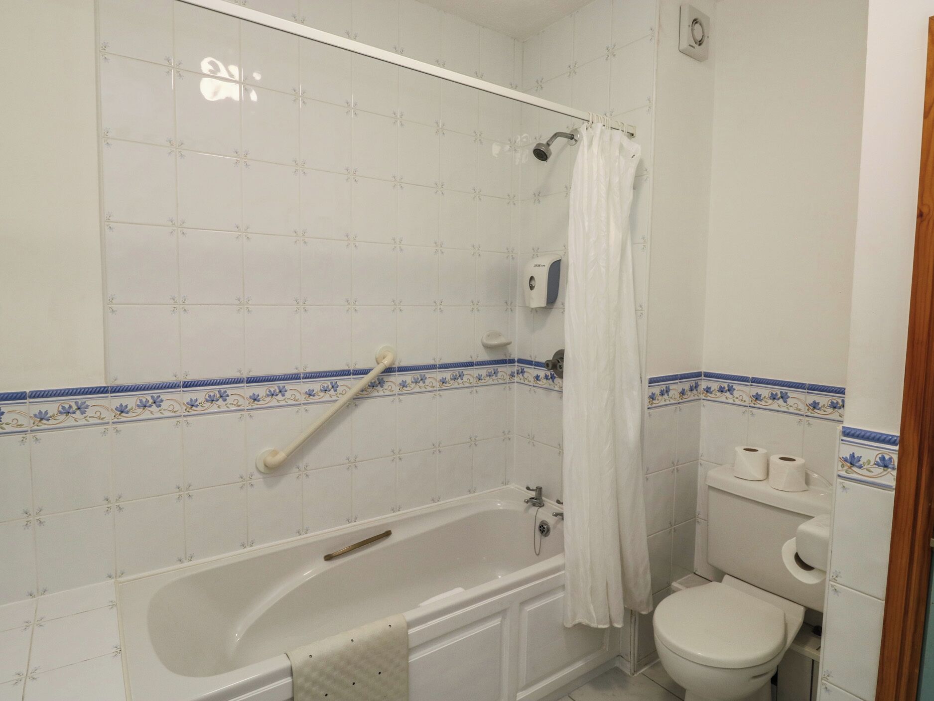 A bathroom with a bathtub, toilet, and shower curtain.