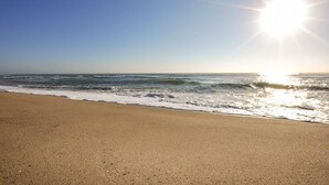A beach with a clear sky and sunlight reflecting off the water.