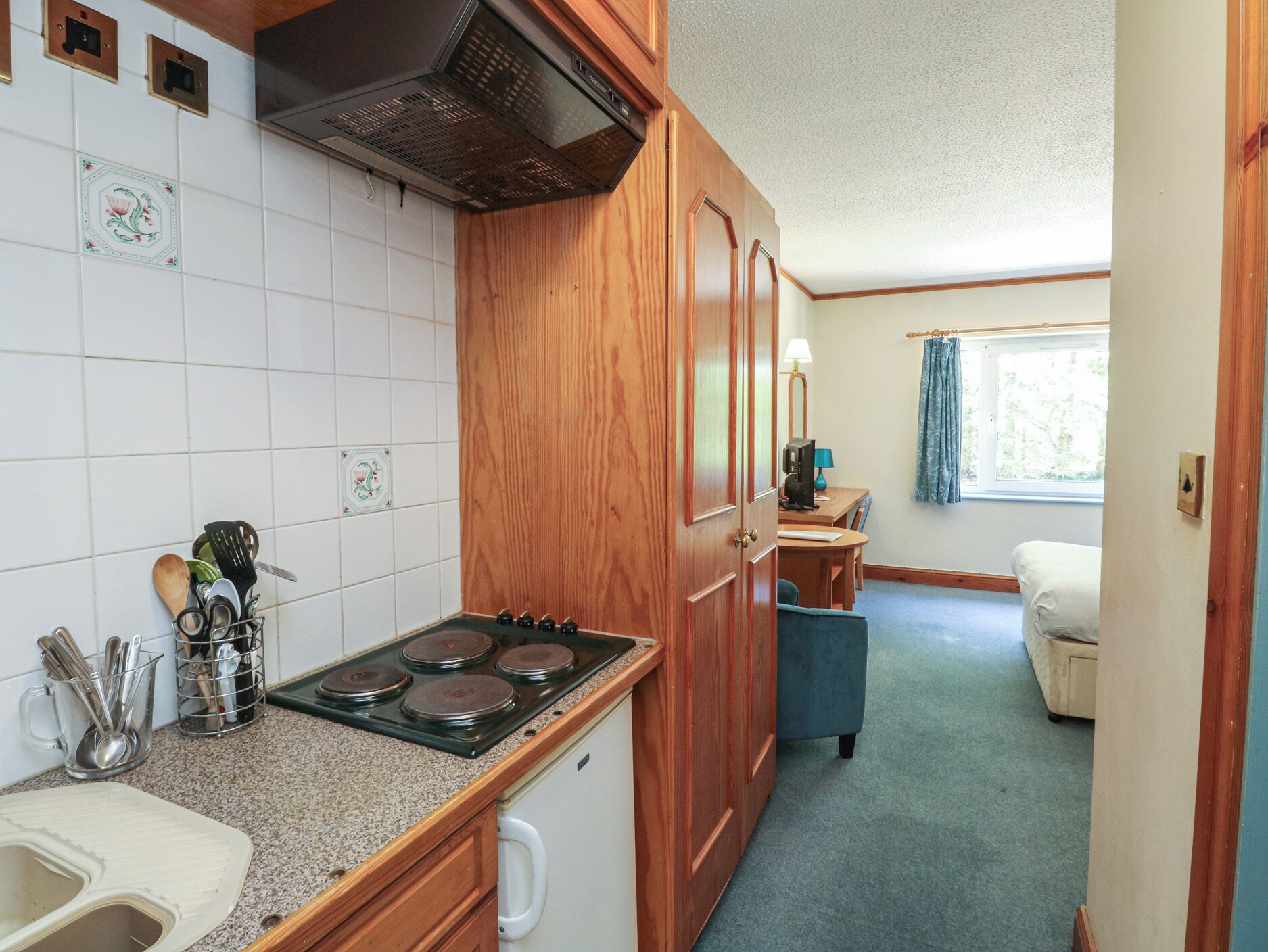 A compact kitchen with a stove, sink, and wooden cabinets.