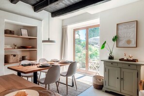 A dining area with a wooden table, chairs, and a view of the outdoors through a glass door. - Casa Mina (Menaggio)