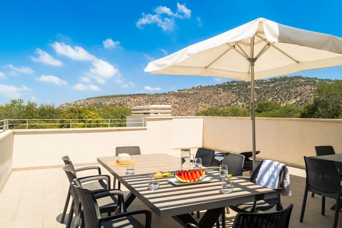 A terrace with a table, chairs, and a large umbrella.