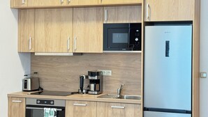Une cuisine moderne dotée d’armoires en bois, d’un réfrigérateur en acier inoxydable, d’un four à micro-ondes, d’une machine à café et d’un grille-pain.