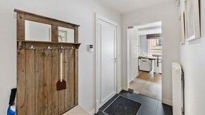 Un pasillo con puerta de madera, un espejo y vista a una cocina.