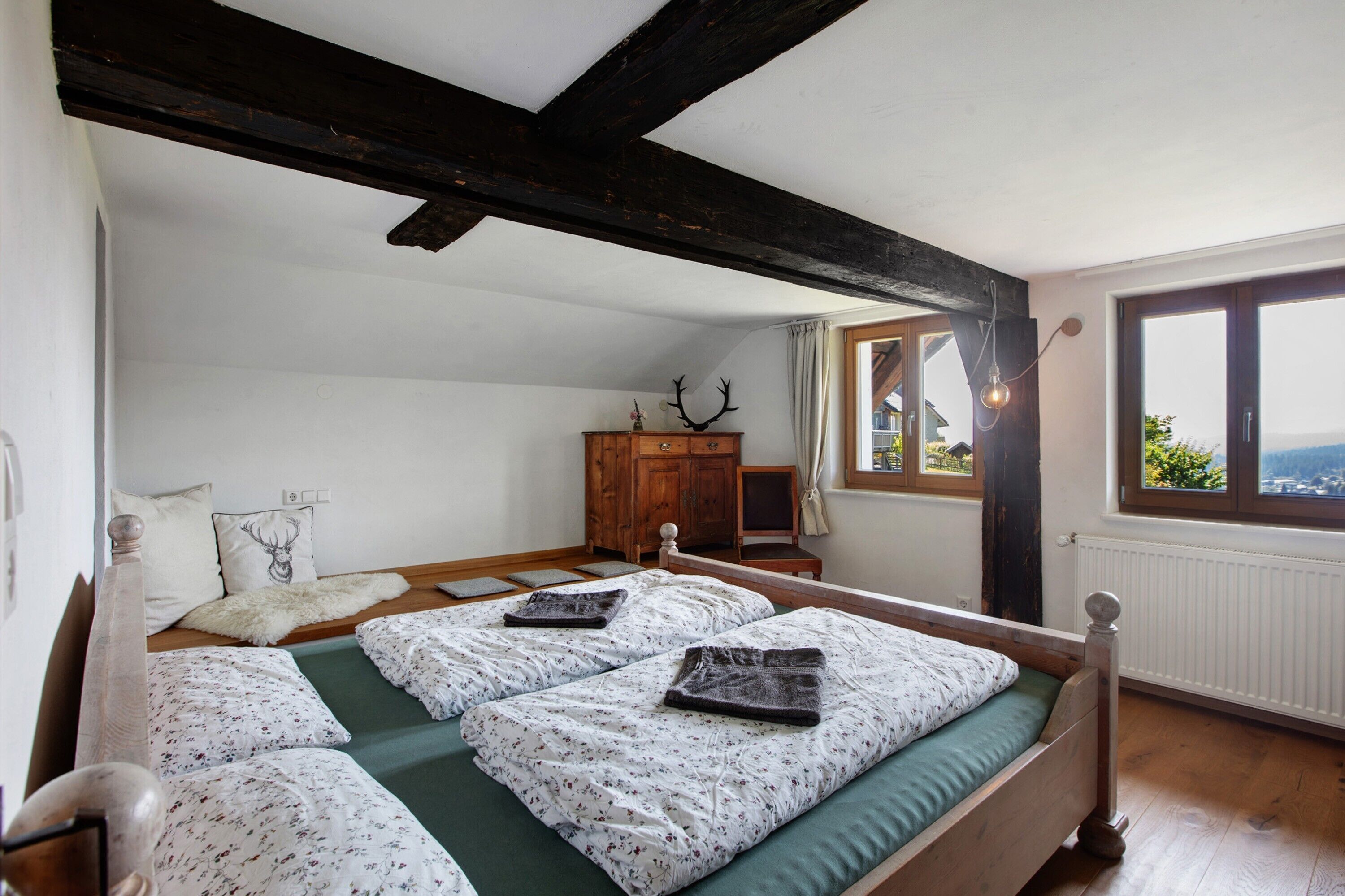 Un dormitorio con una cama y una cómoda de madera, y vistas al exterior a través de una ventana.