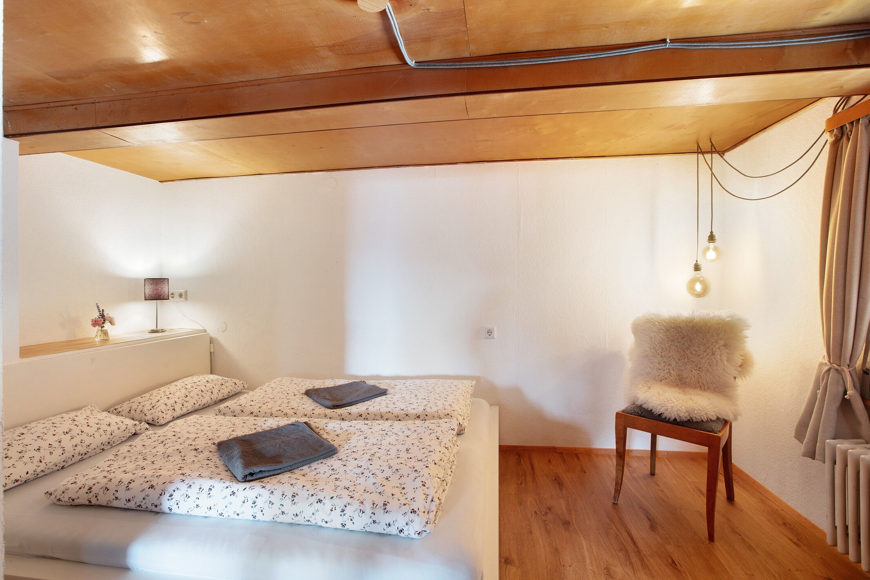 A bedroom with a bed, a chair, a lamp, and a radiator.