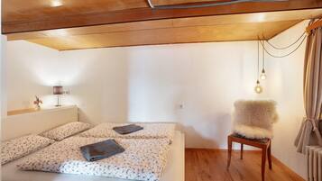 A bedroom with a bed, a chair, a lamp, and a radiator.