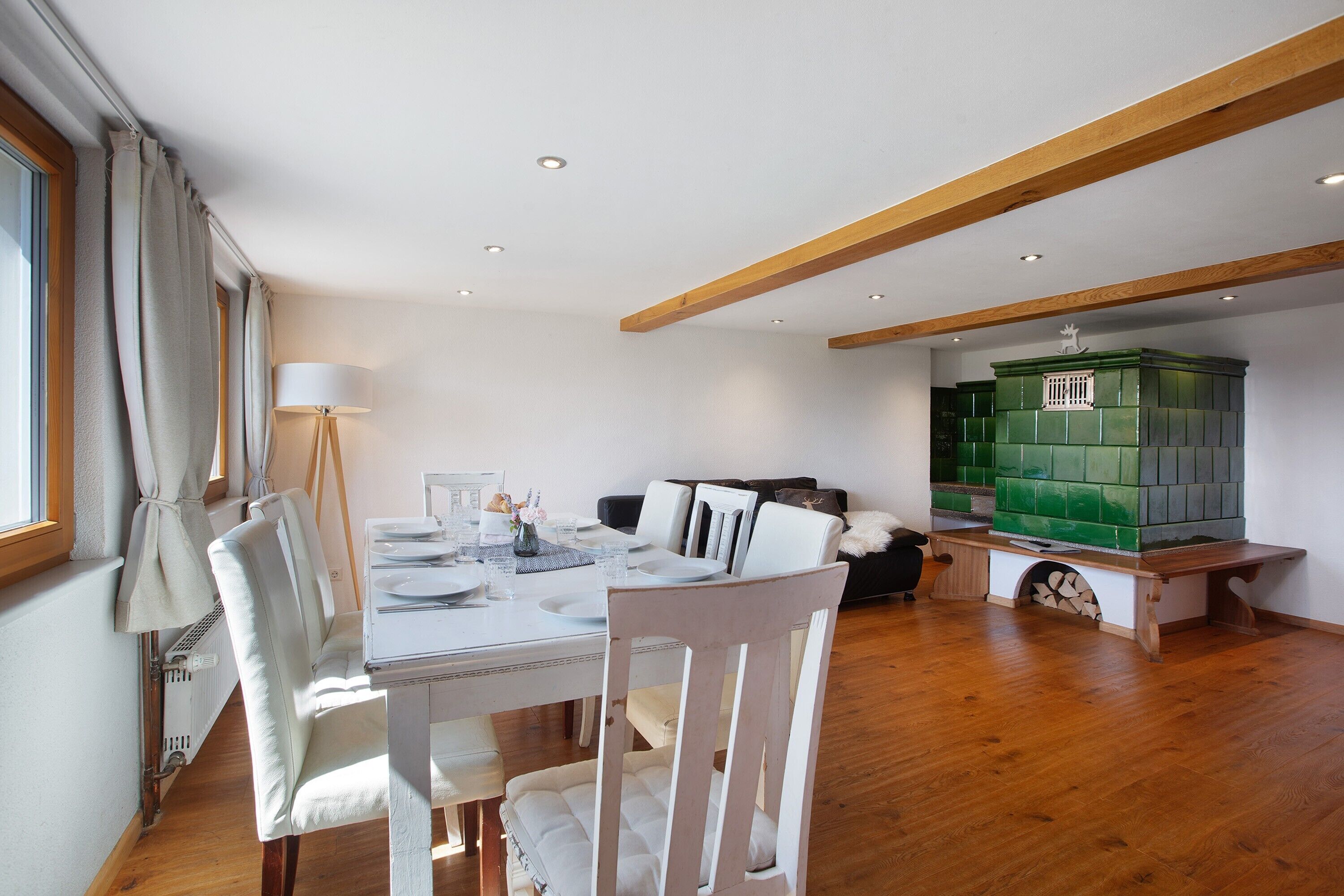 A dining area with a table set for four, a sofa, and a green cabinet.
