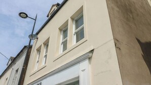 A building with a flat facade, multiple windows, and a visible storefront with signage. - Curwen Apartment (Workington)