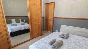 Ein Schlafzimmer mit einem Bett, einem großen Spiegel und einem Holzschrank.