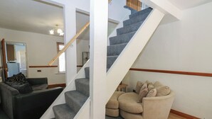 Eine Treppe mit grauen Teppichstufen und weißen Wänden, die zu einer oberen Etage führt.