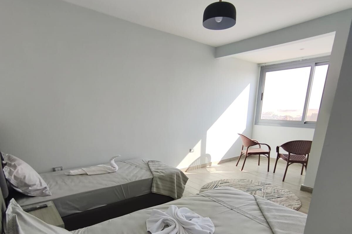Una habitación moderna y bien iluminada con dos camas individuales, una mesita y una silla.