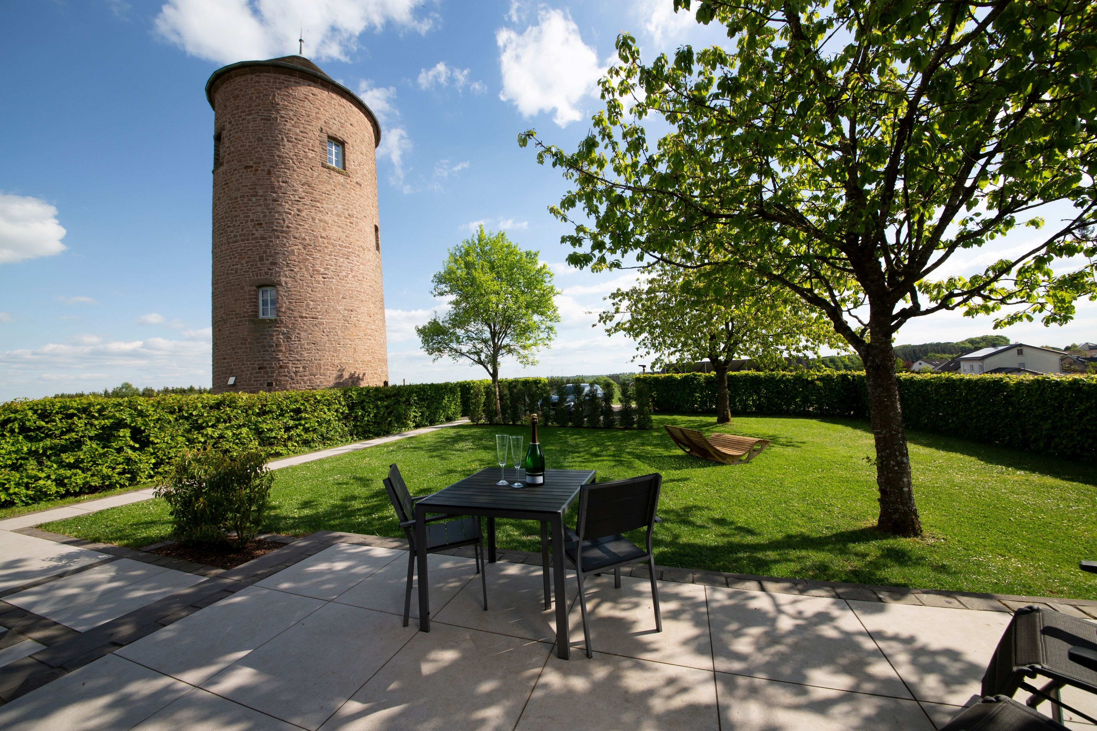 Un patio con una torre de ladrillo, una mesa con sillas y un árbol.