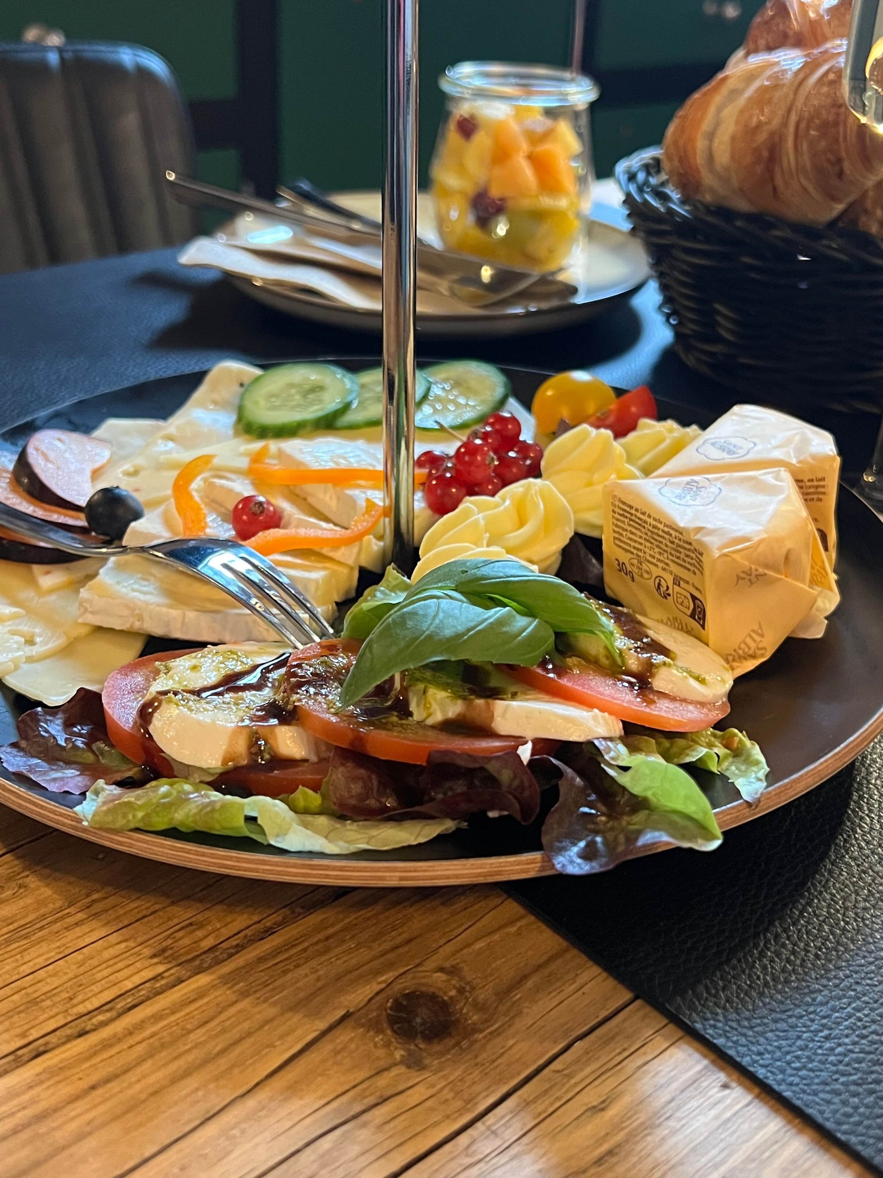 Ein Teller mit einer Auswahl an Speisen, darunter Käse, Gemüse und ein Glas Fruchtsaft.