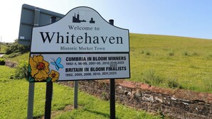 Letrero de bienvenida a Whitehaven, pueblo histórico del mercado, con ganadores de Cumbria en Flor y finalistas de Britain in Bloom.