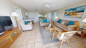 A spacious living room with a television, two sofas, a coffee table, and wicker chairs. - Crescent Arms Vacation Rentals 501S Siesta Key Florida (Sarasota)