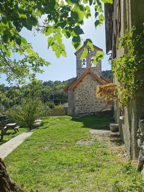 A stone church with a bell tower, surrounded by a grassy area and trees. - SARL SCOP BIENVENUE A L AUBERGE (Sauze)
