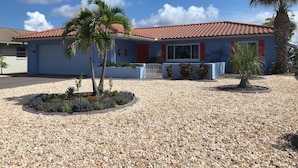 A two-story house with a red-tiled roof, surrounded by gravel and small plants. - Charming 2-bedroom house in lovely New Port Richey with pool. (New Port Richey)