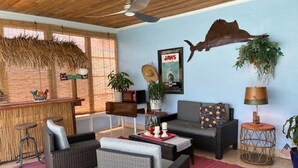 A room with wicker furniture, a bar area, a large fish decoration, and a poster on the wall. - Charming 2-bedroom house in lovely New Port Richey with pool. (New Port Richey)