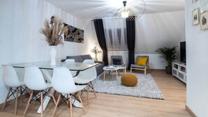 A modern living room with a glass dining table, white chairs, a sofa, and a yellow accent chair. - Superb apartment in the heart of Colmar (Colmar)
