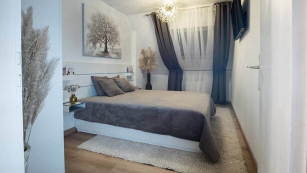 A bedroom with a bed, a nightstand, a vase with dried plants, a painting of a tree, and a chandelier. - Superb apartment in the heart of Colmar (Colmar)