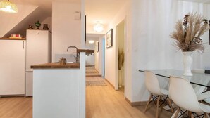 A modern kitchen with white cabinetry, a wooden countertop, and a dining area with a glass table and white chairs. - Superb apartment in the heart of Colmar (Colmar)