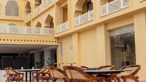 A hotel with a courtyard featuring outdoor seating and a traditional architectural style. - Haut Monde Rajputana Palace (Behror)