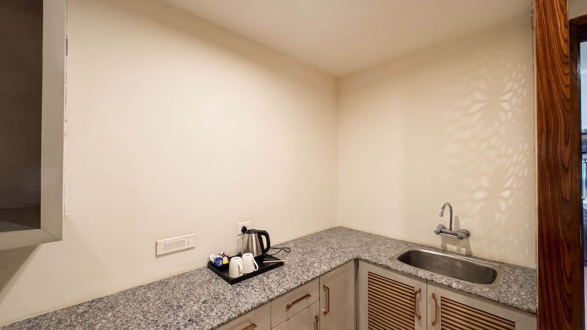 Een kleine keuken met een granieten aanrecht, een spoelbak en een koffiezetapparaat.