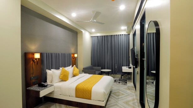 A hotel room with a bed, bedside table, lamp, and a mirror. - Hotel Breeze Bay ex (Mumbai)