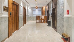 A hotel lobby with a marble floor, wooden doors, a reception desk, and a ceiling fan. - Hotel Breeze Bay ex (Mumbai)