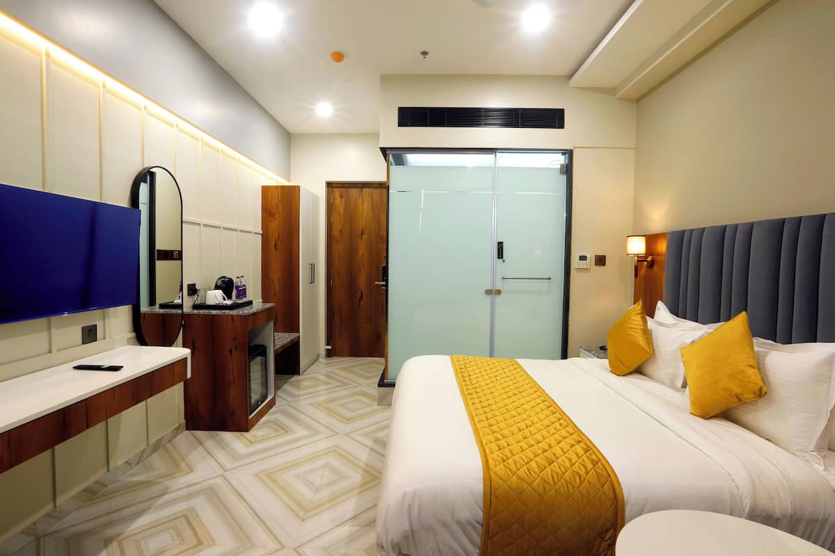 A hotel room with a bed, bedside table, mirror, wardrobe, and a bathroom with a toilet and sink.