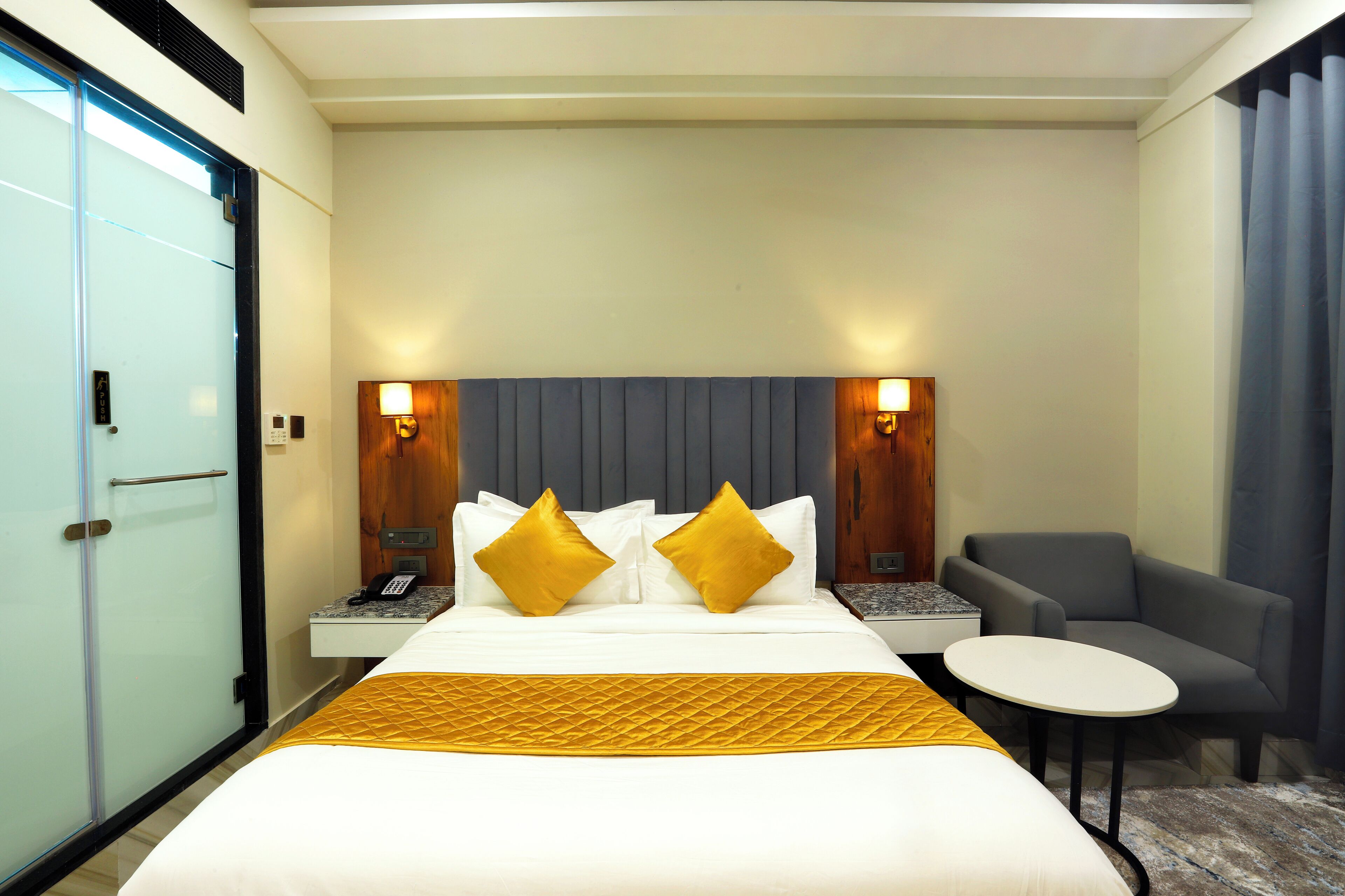 A hotel room with a bed, bedside tables, a chair, and a small table.