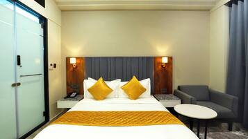A hotel room with a bed, bedside tables, a chair, and a small table.