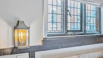 Una stanza con un'ampia finestra, un lampadario a parete e una panca in legno.