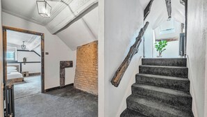 A staircase with a rustic design, a brick wall, and a modern room with a bed and a plant. - Chester Rose, Chester (Chester)