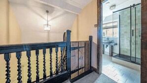 A staircase with a black balustrade leading to a bathroom with a glass shower enclosure. - Chester Rose, Chester (Chester)