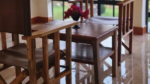 Comedor con muebles de madera y un ventanal con vistas a zonas verdes.