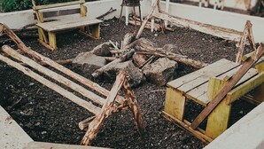 Un área de estar al aire libre rústica con bancos de madera y un brasero.