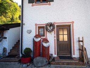 Um edifício com porta marrom, uma pequena janela e uma grinalda na parede.