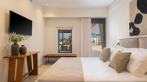 Una habitación de hotel moderna con una cama grande, un televisor de pantalla plana montado en la pared, una mesita de noche de madera y vistas al exterior a través de una puerta corrediza.