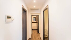 A narrow hallway with wooden flooring, white walls, and a ceiling light.