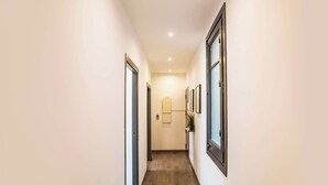 A narrow hallway with wooden flooring and white walls.