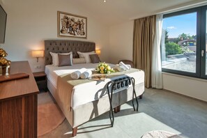 A hotel room with a large bed, a bedside table, a desk, a chair, a window with a view, and a painting on the wall. - Villa Kim Momjan With Pool and Spa (Buje)