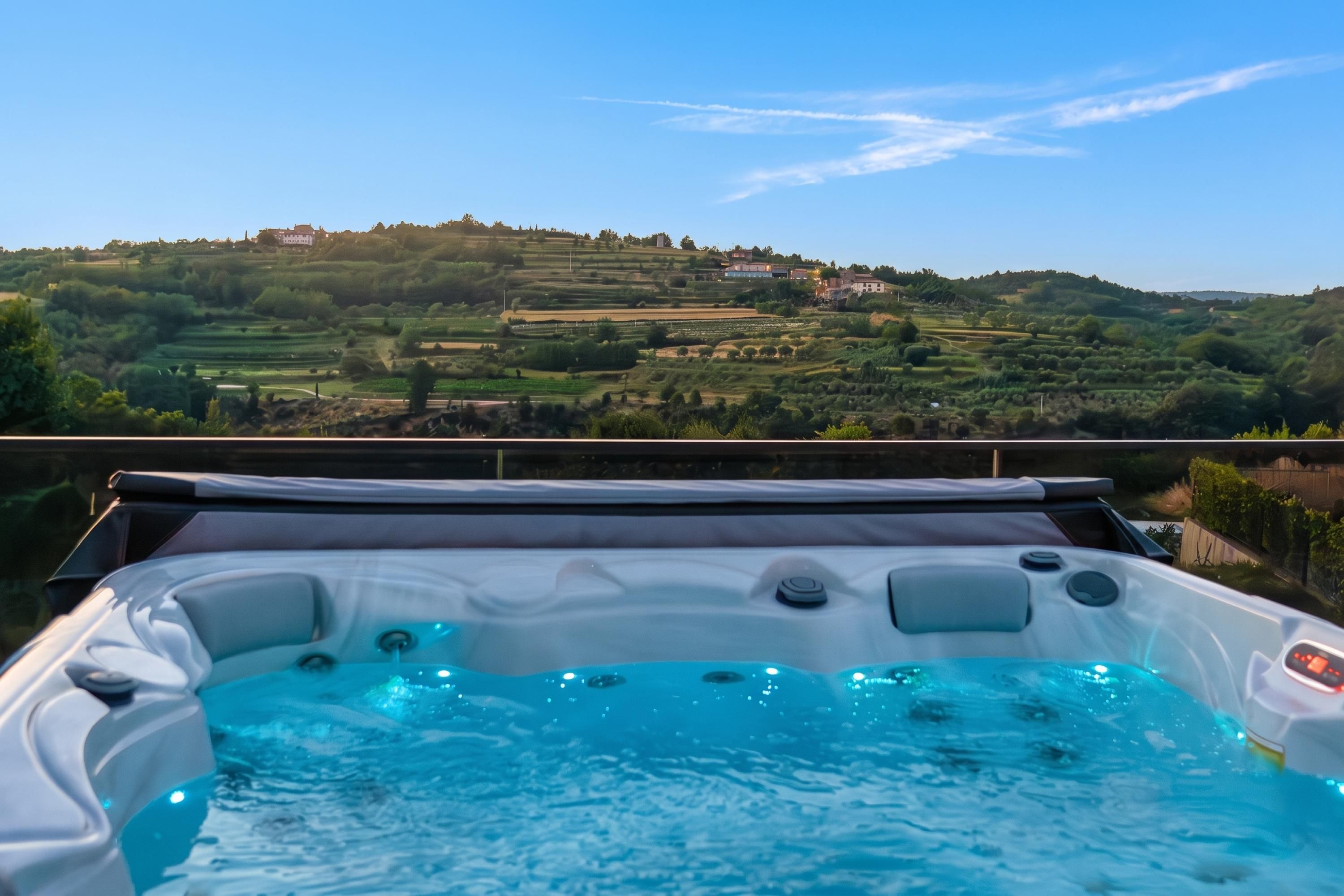 Ein Whirlpool mit Blick auf eine hügelige Landschaft und Gebäude in der Ferne.