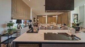 A modern kitchen with a large island, built-in appliances, and a dining area with a sofa and table set for a meal. - Villa Kim Momjan With Pool and Spa (Buje)